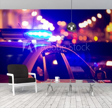 Picture of Blue light flasher atop of a police car City lights on the background
